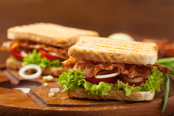 Toasted sandwich with bacon, tomato, cucumber and lettuce.