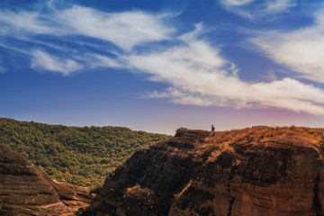 Man with backpack on the edge of the rock look on the monasteries of Meteora