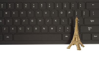 computer keyboard and Eiffel Tower in miniature. concept for online shopping or travel to Paris, France.