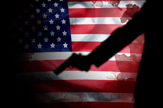 handgun in gunman hand with blood stain on American flag. reform gun control in America concept