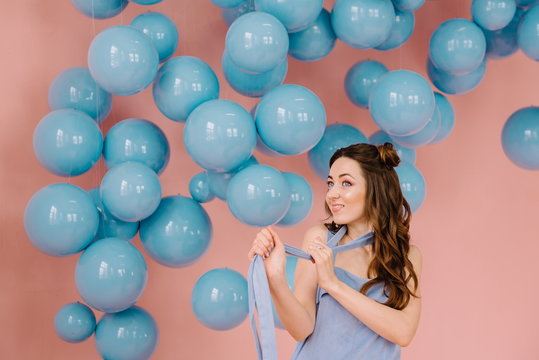 A tender girl in a blue dress, in a pink room playing a blue ribbon