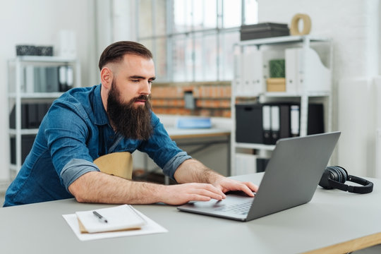 Casual bearded man sitting working on a laptop