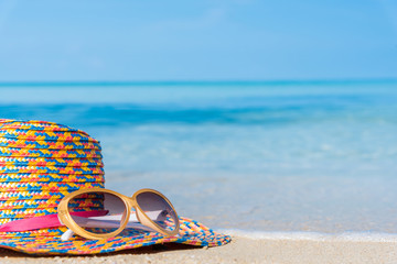 sunglasses and straw hat with blur blue sea and sky background - holiday concept