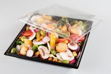traditional salad in black plastic container isolated on white background