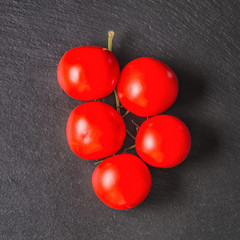 view from above of beautiful branch red tomatoes on slate stone background, close up