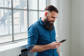 Smiling man reading a text message on his mobile