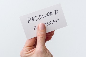 Woman's hand holds a password on paper, that covers the password with finger