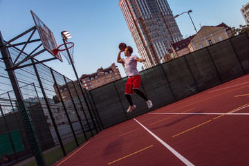 It is time to win! Full length side view of young man in sportswear playing basketball on basketball court outdoors © MARIIA