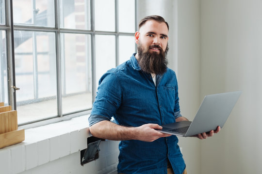 Relaxed bearded man using a handheld laptop