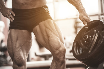 Close-up of bodybuilders muscular legs. Athlete man doing workout exercise in gym.