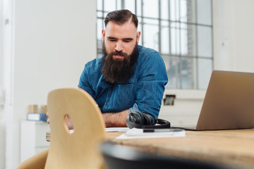 Casual businessman sitting reading paperwork