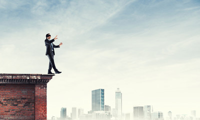 Danger and risk concept with businessman making step from edge