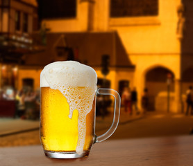 Mug with beer on the background of a outside bar.