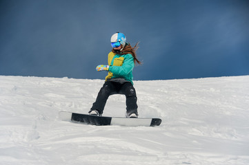 Fototapeta na wymiar Female snowboarder riding down the mountain slope