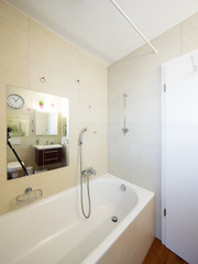Bathtub in bathroom with large tiles
