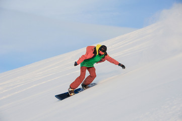 Active snowboarder in sportswear riding on the snowy slope