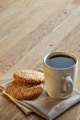 Porcelain teacup with chocolate chips cookies on cotton napkin on a rustic wooden background, top view