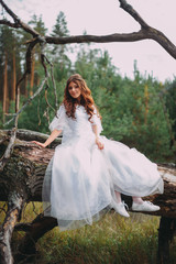 beautiful bride in white dress sitting on a tree