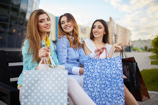 Beautiful girls with packages after shopping A picture of a group of happy friends shopping in the city. Girls walking around the city after shopping. good mood. Evening light. shopping concept