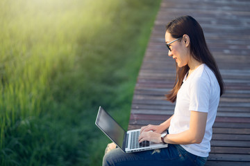 Happy woman relaxing and working on the bridge in the rice field in the morning.