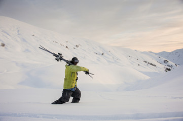 Side view of professional male snowboarder walking in mountains