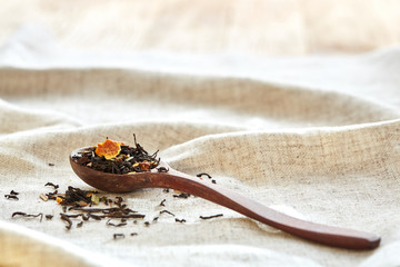 Closeup of a wooden spoon filled with scattered tea leaves, shallow depth of field, top view