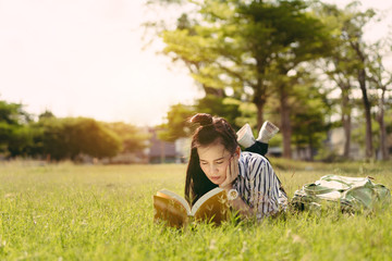 Naklejka na ściany i meble Young woman student reading book in university campus college and serious study learning knowledge at park outdoor