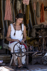 Fototapeta na wymiar Woman using a spinning wheel, in a street market