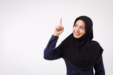 confident happy smiling successful muslim business woman pointing up; studio portrait of islamic business woman pointing finger; asian businesswoman, female business person points up to space