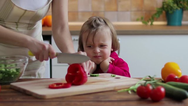 Cute kid girl not wanting to eat healthy food at kitchen