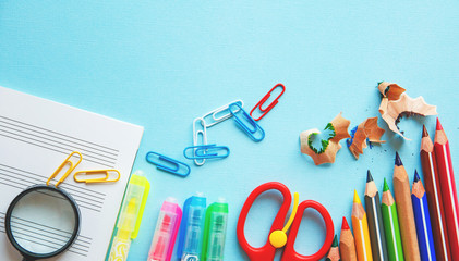 Different school or office supplies on a blue background. Education or business concept. Flat lay.