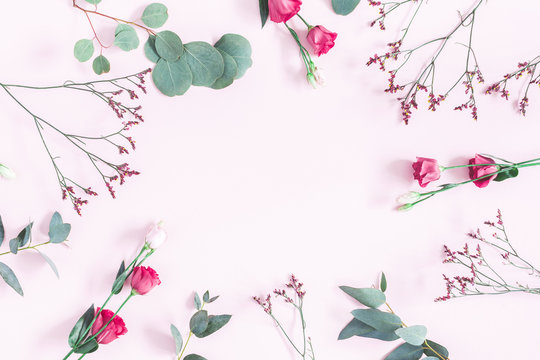 Flowers composition. Frame made of various pink flowers and eucalyptus branches on pink background. Flat lay, top view, copy space