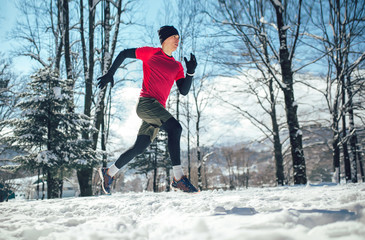 Young man running at winter in park