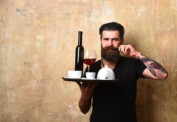 Waiter with glass and bottle of wine by tea set
