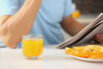 man in the kitchen eating a juice newspaper