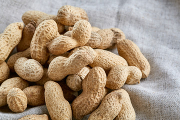 Heap of peanuts on light tablecloth, close-up, shallow depth of field, selective focus, macro