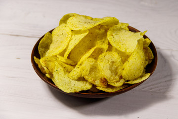 Plate of potato chips on white wooden table