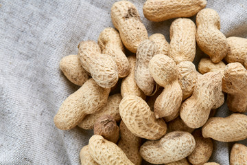 Heap of peanuts on light tablecloth, close-up, shallow depth of field, selective focus, macro
