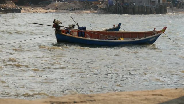 Small fishing boats sail along the lush sea on waves. Fishermen catch fish in the sea