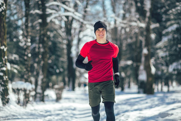 Young man running at winter in park