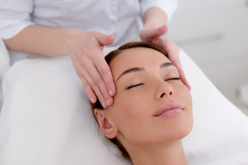 partial view of young woman getting head massage made by cosmetologist in salon