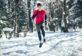 Young man running at winter in park