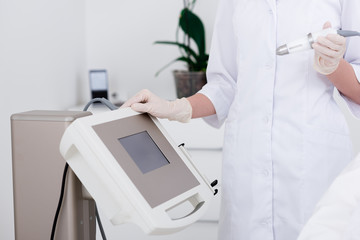 partial view of cosmetologist and cosmetology apparatus in salon