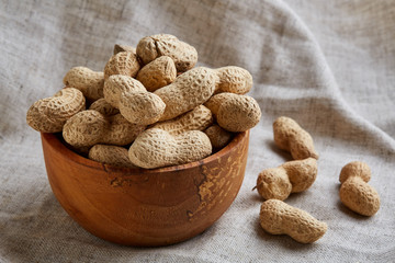 Unpeeled peanuts in ceramic bowl closeup, selective focus