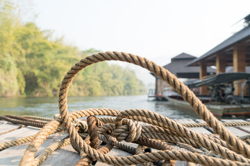 Fototapeta premium closeup thick rope tie on the wooden terrace near river