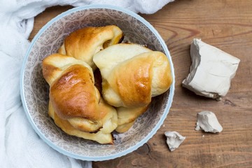 homemade yeast croissants in a ceramic bowl and raw yeast on a wooden background
