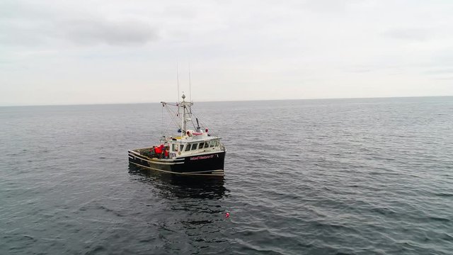 Aerial of large fishing boats checking their lobster traps in ocean