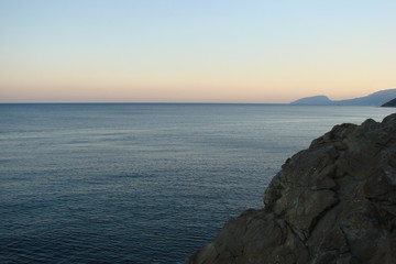 The landscape of the Black Sea near the rocky shore at sunset.