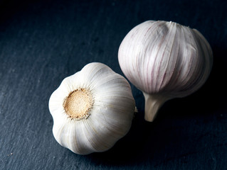 Close up view of two garlic bulbs arranged on a black piece of board, shallow depth of field, selective focus, macro