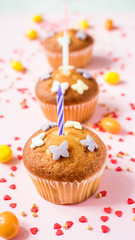 Birthday cupcakes with candles on the table. Pink background.